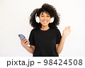 Portrait of happy young woman in headphones holding smartphone 98424508