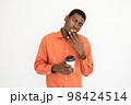 Portrait of tired young man holding coffee cup and yawning 98424514