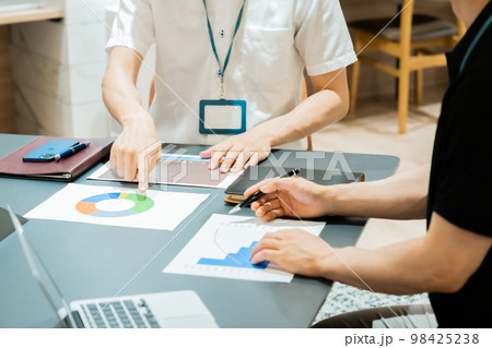 プリントをした用紙を見ながら、コンサルティングするビジネスマン 98425238