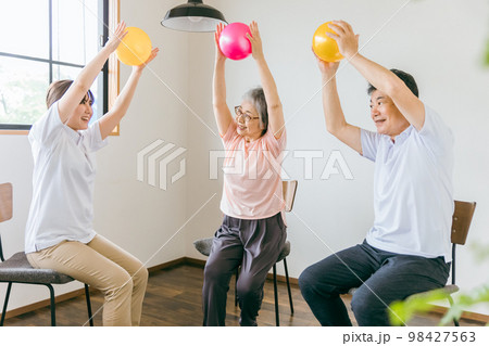 病院・デイサービスでボール体操・運動・リハビリするシニア・高齢者の男女と理学療法士・運動指導員 98427563