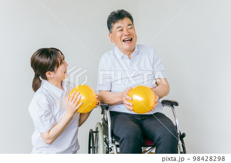 家でボール体操・運動・リハビリするシニア・高齢者の男女と理学療法士・介護士・トレーナー 98428298