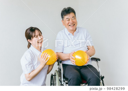 老人ホームでボール体操・運動・リハビリするシニア・高齢者の男性と理学療法士・介護士・トレーナー 98428299