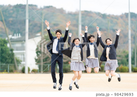 校庭でジャンプする女子高生と男子学生 98429693