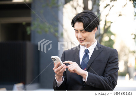 外でスマホをタップするビジネスマン アップ 外でスマホをタップするビジネスマン アップ 98430132