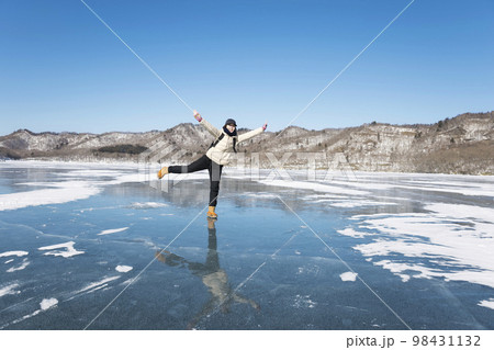 チェーンスパイクを履いて湖の氷上ではしゃぐ女性 チェーンスパイクを履いて湖の氷上ではしゃぐ女性 98431132