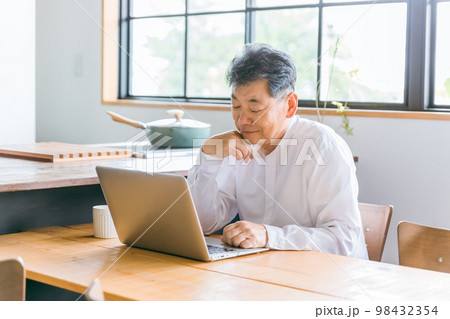 家のダイニングでノートパソコンを使う高齢者男性(考える・悩む) 家のダイニングでノートパソコンを使う高齢者男性(考える・悩む) 98432354