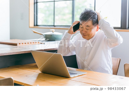 家でパソコンを使いながら困る高齢者男性(故障・修理・詐欺・悩む) 98433067