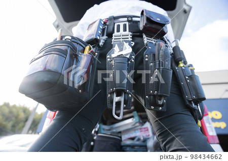 作業車の前で腰道具を装着する作業員男性 98434662