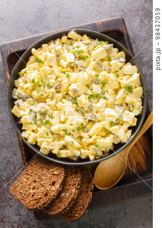 Eiersalat German Egg and Apple Salad served with bread closeup on the wooden board. Vertical top view 98437059