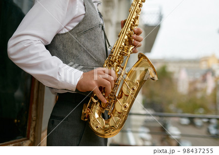 Saxophonist playing music outdoors, closeup saxophone in musician hand 98437255