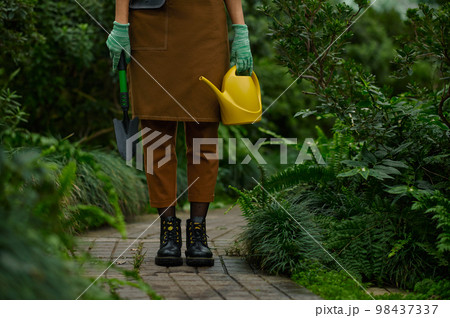 Cropped shot of gardener holding garden tool view on leg Cropped shot of gardener holding garden tool view on leg 98437337