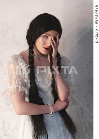 Young girl with dark hair in a white vintage dress from the 19th century. Studio shooting Young girl with dark hair in a white vintage dress from the 19th century. Studio shooting 98437436