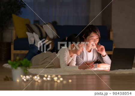 夜リビングで寝転がってパソコンを見る小学生の女の子とママ 夜リビングで寝転がってパソコンを見る小学生の女の子とママ 98438054