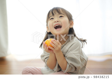 みかんを持つ女の子 98438215