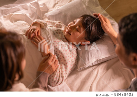 夜 子供を寝かしつけるパパとママ 夜 子供を寝かしつけるパパとママ 98438403