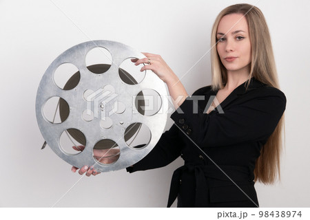 A young woman movie executive is holding an old film reel 98438974
