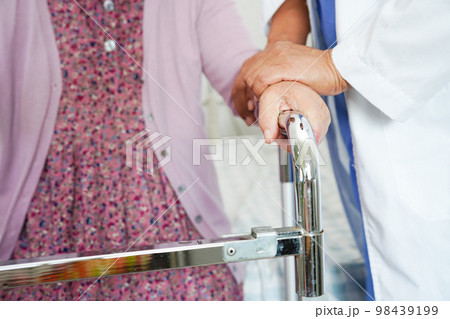 Doctor help Asian elderly woman disability patient walk with walker in nursing hospital, medical concept. 98439199