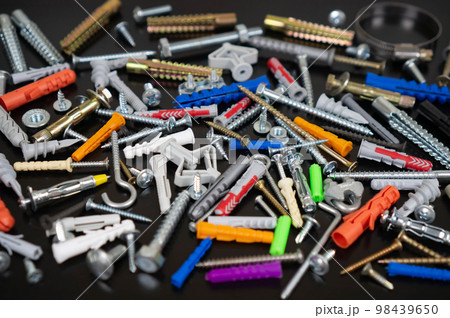 Different types of fasteners on a dark wood background. Front view. Different types of fasteners on a dark wood background. Front view. 98439650