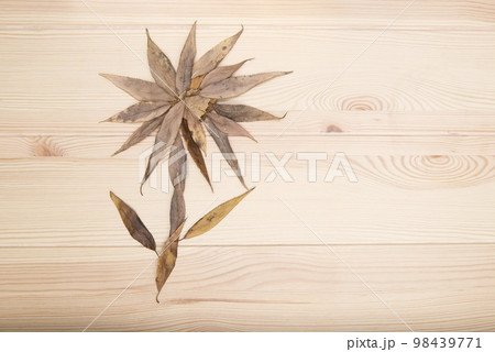Flower. Image of a flower collected from small autumn leaves on a textured wooden surface of the table. Flower. Image of a flower collected from small autumn leaves on a textured wooden surface of the table. 98439771