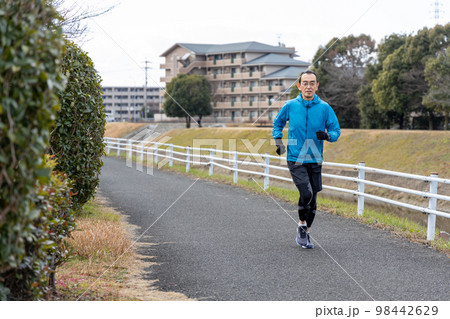 休日に川沿いの遊歩道で趣味のジョギングをするシニア男性 休日に川沿いの遊歩道で趣味のジョギングをするシニア男性 98442629