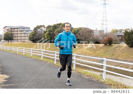 休日に川沿いの遊歩道で趣味のジョギングをするシニア男性 98442631