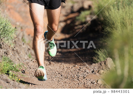 Trail running athlete exercising for fitness and health outdoors on mountain pathway, closeup of running shoes in action 98443301
