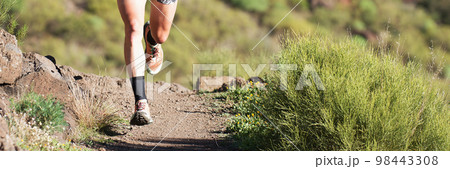 Trail running athlete exercising for fitness and health outdoors on mountain pathway, closeup of running shoes in action 98443308