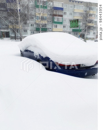 Car covered with snow, close-up. A passenger car in winter was covered with snow after a snow storm. Car in the parking lot near the house 98443954