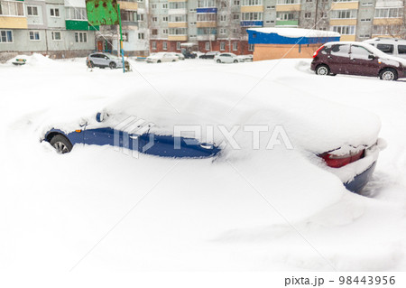 Car covered with snow, close-up. A passenger car in winter was covered with snow after a snow storm. Car in the parking lot near the house 98443956