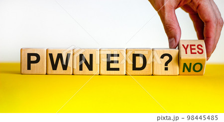 Have I Been Pwned - slang for password owned. Male hand flips a wooden cube and changes the inscription 'pwned yes' to 'pwned no'. Beautiful yellow table, white background, copy space. 98445485
