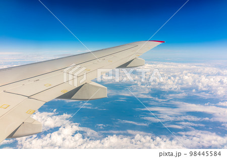 View from the airplane window at a beautiful cloudy sky and the airplane wing View from the airplane window at a beautiful cloudy sky and the airplane wing 98445584