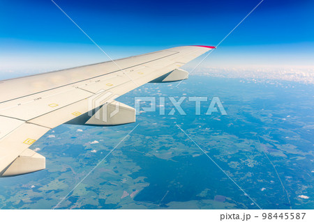 View from the airplane window at a beautiful cloudy sky and the airplane wing View from the airplane window at a beautiful cloudy sky and the airplane wing 98445587