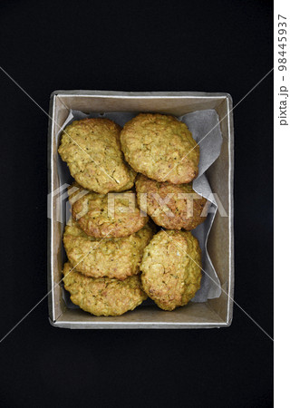 Delicious oatmeal cookies in a cardboard box on a black background. Sweet cookies. A sweet snack for tea. 98445937