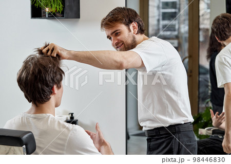 Barber talking to caucasian man while sitting in chair 98446830