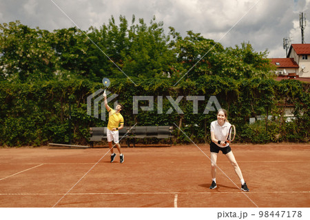 Photo of male and female tennis players during game. Couple playing a match. Man wearing yellow t-shirt and woman the white one. 98447178