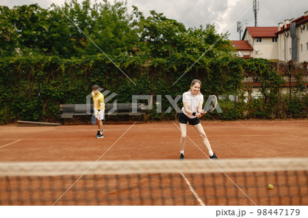 Photo of male and female tennis players during game. Couple playing a match. Man wearing yellow t-shirt and woman the white one. 98447179