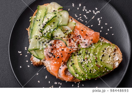 Fresh tasty sandwich with salmon, avocado and sesame and flax seeds 98448693