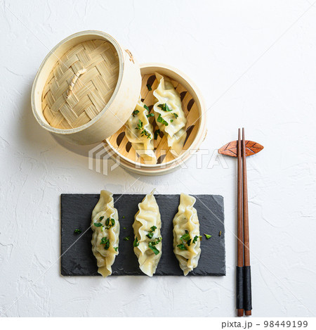 steamed dumpling or Japanese gyoza, dumplings snack in traditional wooden steamer and black stone slate on white texture stone background top view steamed dumpling or Japanese gyoza, dumplings snack in traditional wooden steamer and black stone slate on white texture stone background top view 98449199
