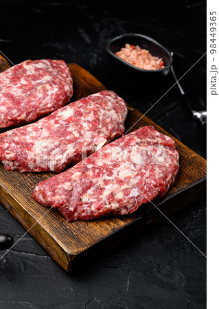 Raw Minced Meat Cutlets set, on black dark stone table background Raw Minced Meat Cutlets set, on black dark stone table background 98449365