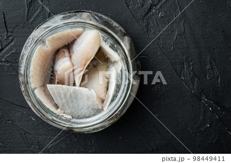 Pickled herring, in glass jar, on black background, top view flat lay, with copyspace and space for text Pickled herring, in glass jar, on black background, top view flat lay, with copyspace and space for text 98449411