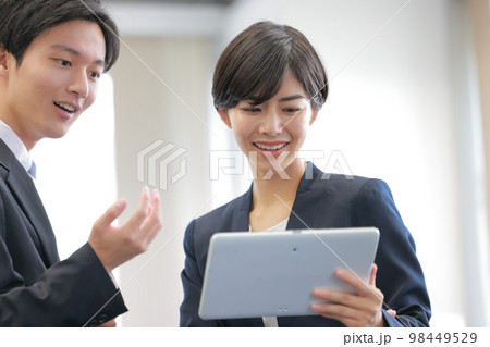 タブレットを見ながら打ち合わせるビジネスパーソン男女_クローズアップ4 98449529
