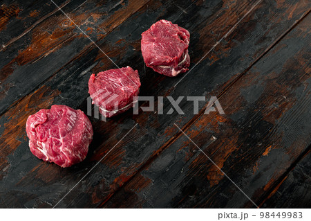 Fresh raw fillet minion steaks marbled beef with rosemary and garlic, on old dark  wooden table background, with copy space for text 98449983