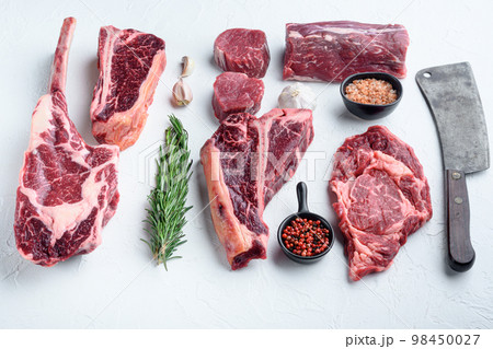 Fresh raw Prime Black Angus beef marbled and dry aged steaks, tomahawk, t bone, club steak, rib eye and tenderloin cuts, on white stone background Fresh raw Prime Black Angus beef marbled and dry aged steaks, tomahawk, t bone, club steak, rib eye and tenderloin cuts, on white stone background 98450027