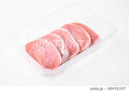 Uncooked pork chop, in plastic pack container, on white stone table background, with copy space for text 98450197