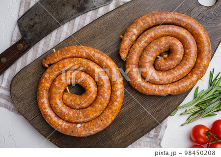 Traditional raw spiral pork sausages, on gray concrete table background, top view flat lay Traditional raw spiral pork sausages, on gray concrete table background, top view flat lay 98450208