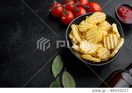 Delicious crispy potato chips, on black stone background, with copy space for text Delicious crispy potato chips, on black stone background, with copy space for text 98450257