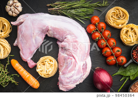 Fresh meat. Whole rabbit ready to cook stew tagliatelle, on black stone background, top view flat lay Fresh meat. Whole rabbit ready to cook stew tagliatelle, on black stone background, top view flat lay 98450364