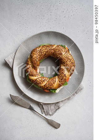 Bagel simit, breakfast, with lettuce, tomato olive and cheese, on gray concrete table background, top view flat lay, with copy space for text 98450397