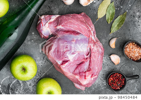 Raw pork meat and ingredients for roast, with apple dry cider, on black dark stone table background, top view flat lay Raw pork meat and ingredients for roast, with apple dry cider, on black dark stone table background, top view flat lay 98450484