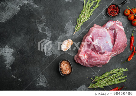 Raw pork meat with herbs, on black dark stone table background, top view flat lay, with copy space for text 98450486